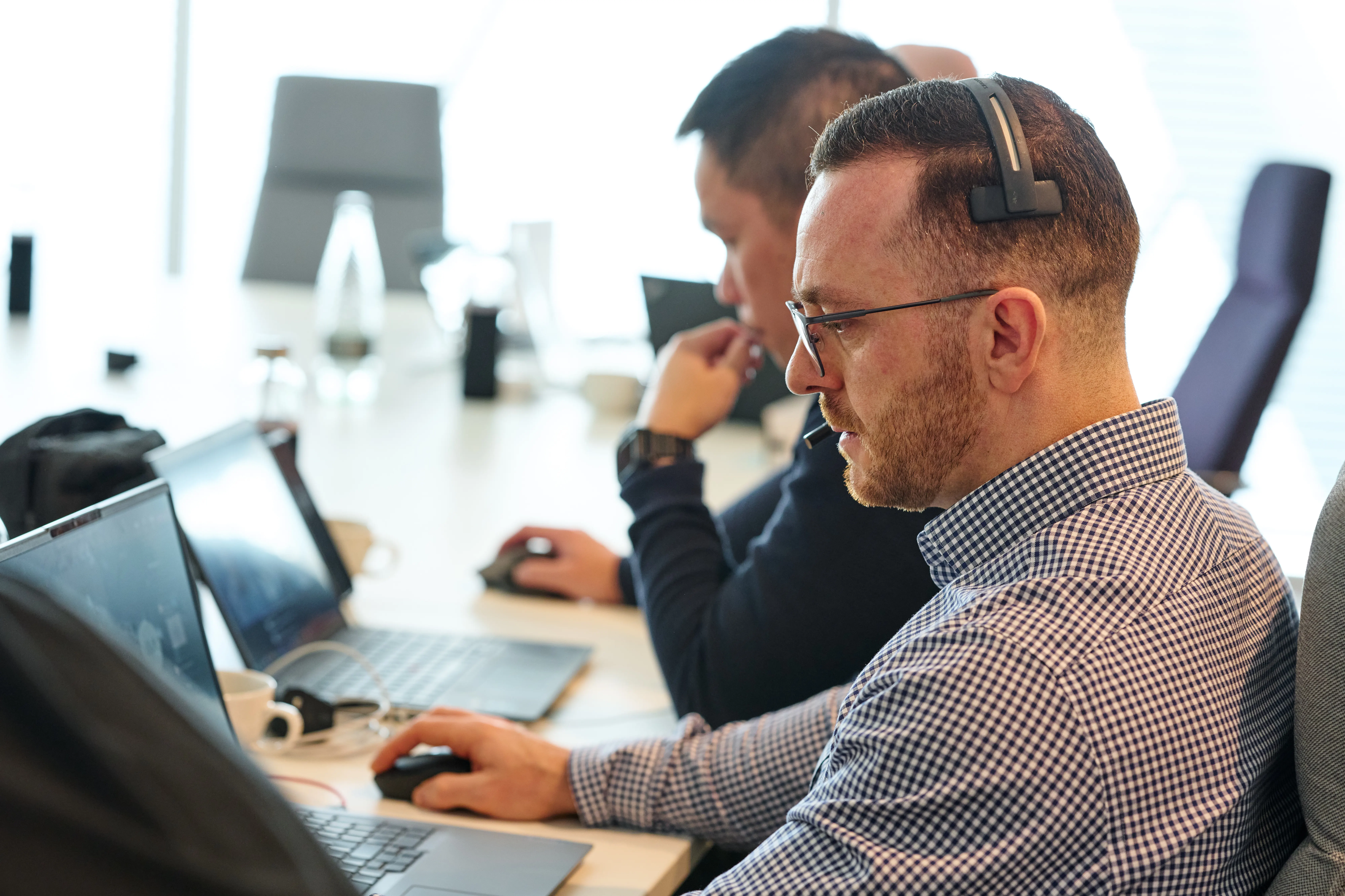 A man with a telecoms headset on using a laptop